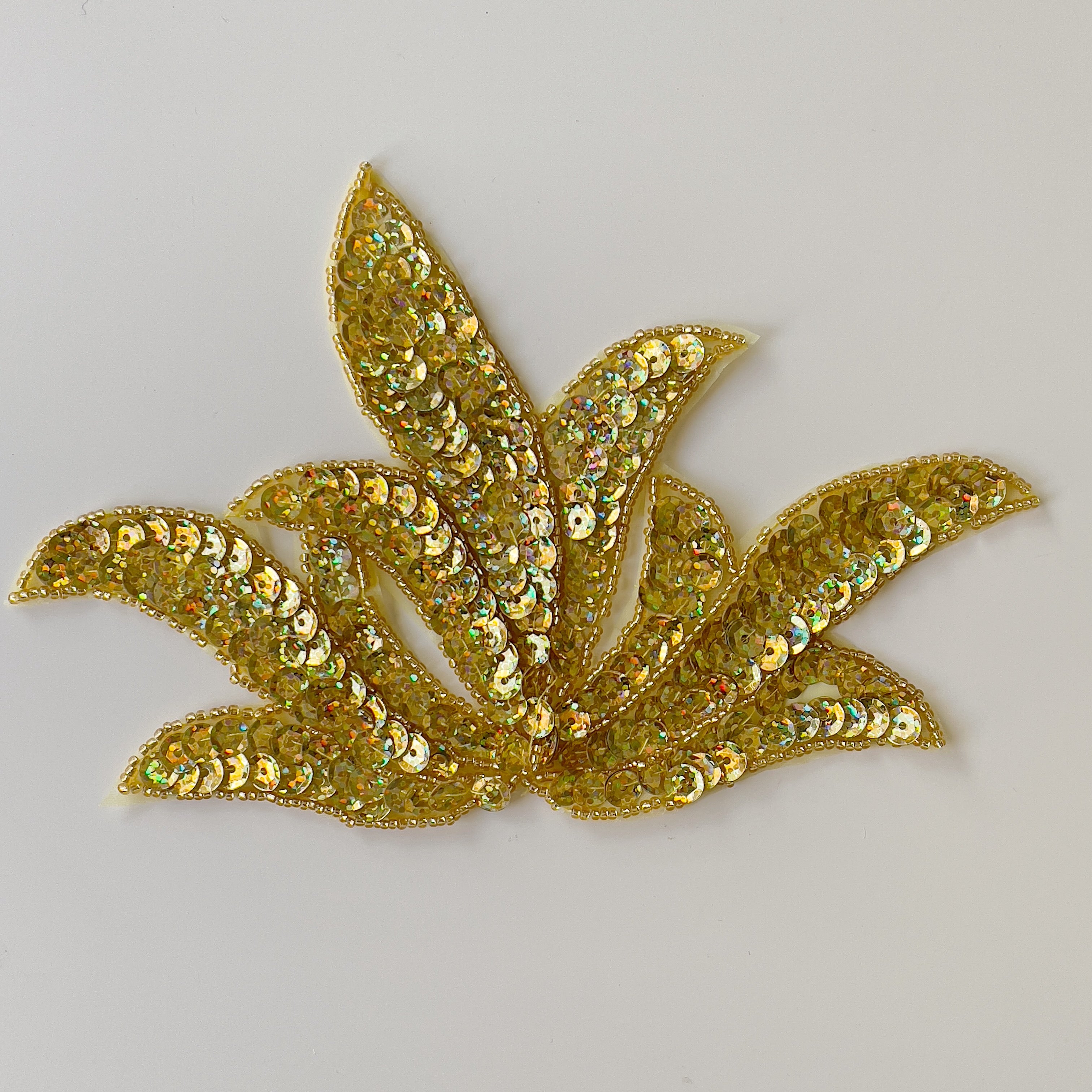 Leaf shaped applique filled with gold hologram sequins.