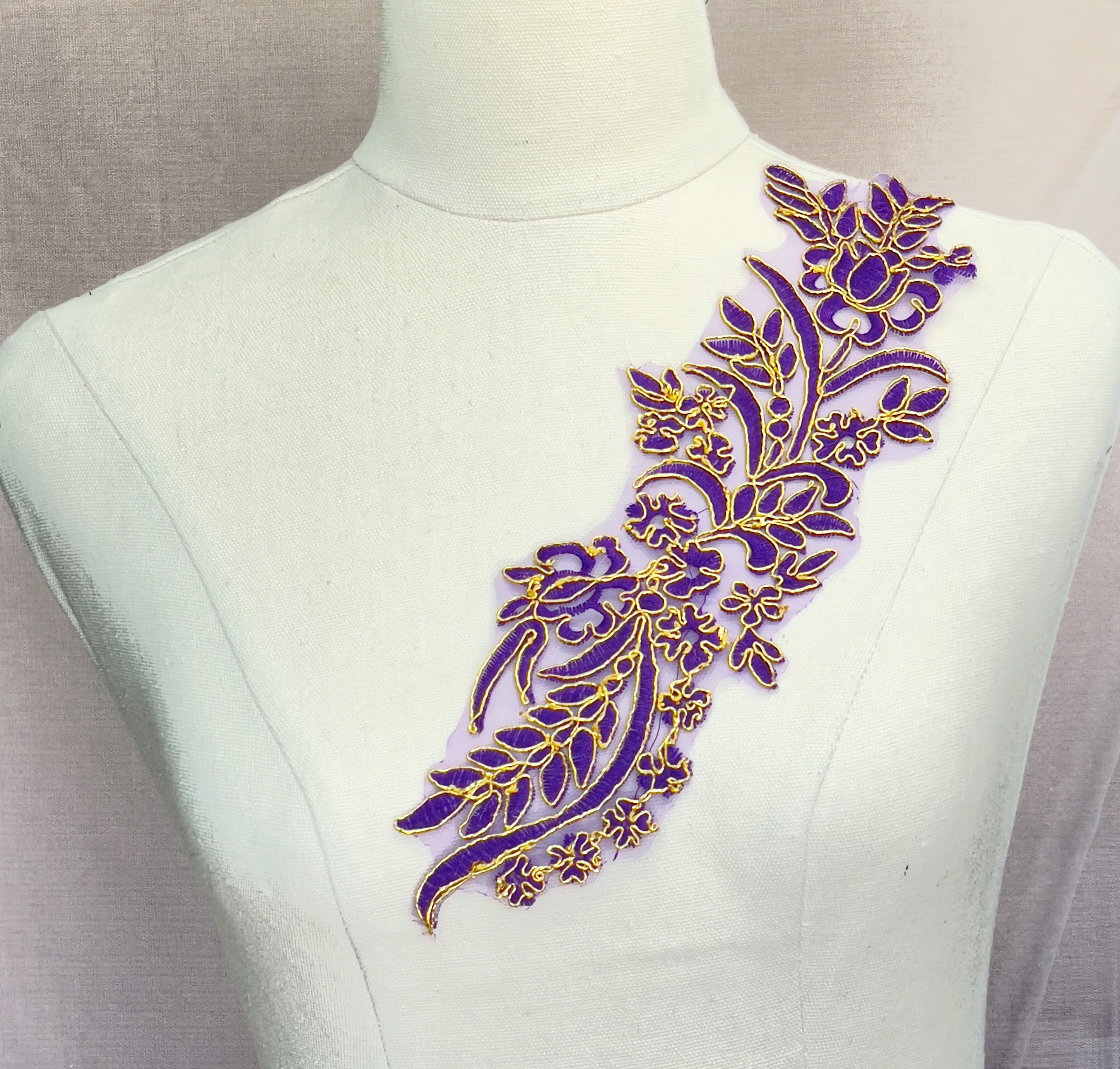 Single floral applique with deep purple thread embroidered onto purple organza and edged with metallic gold cord.  