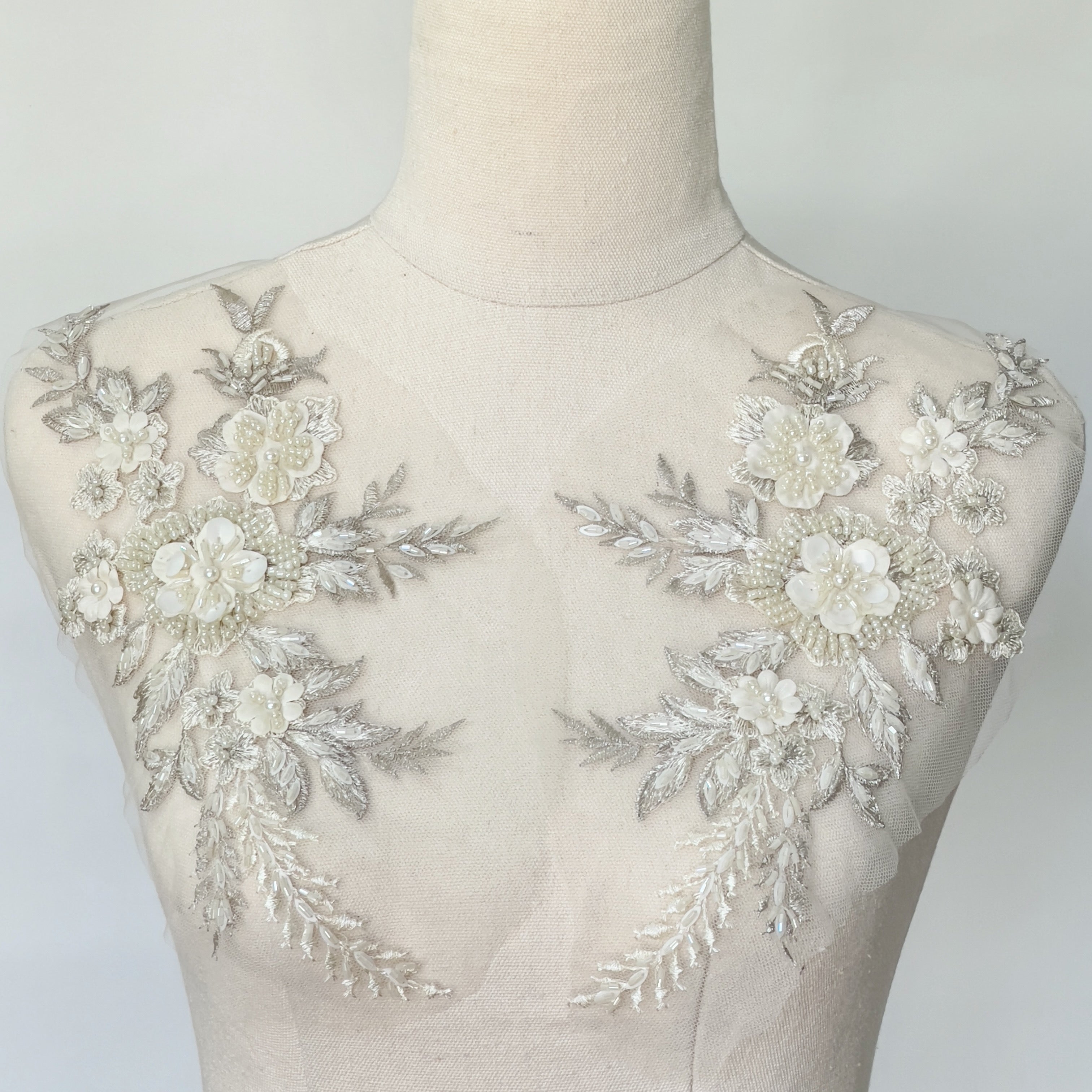Cream and ivory beaded floral applique pair displayed on a mannequin.
