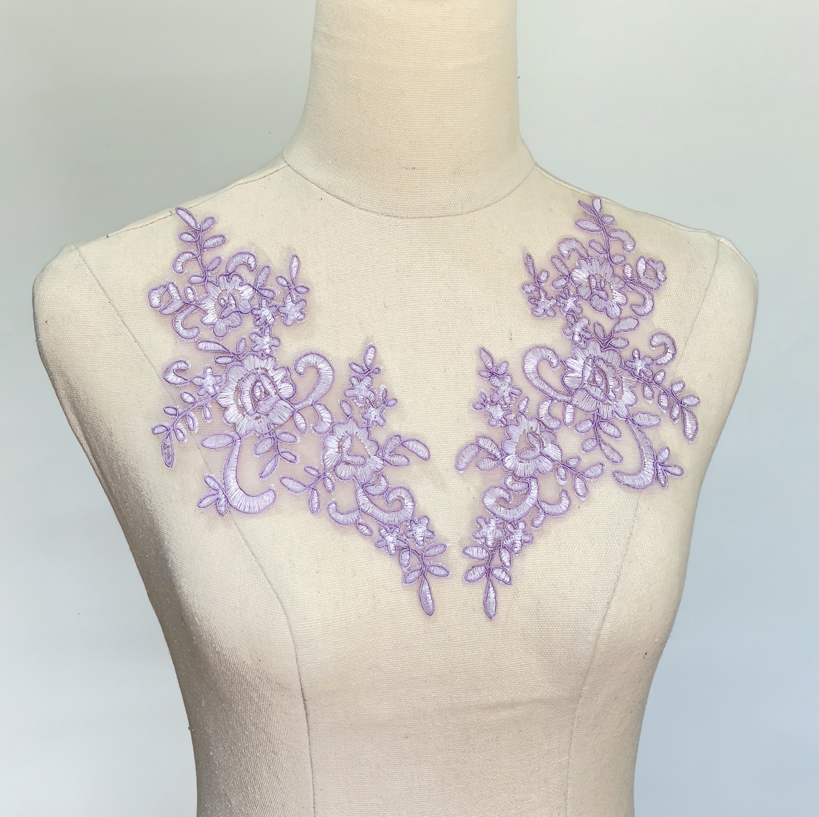 Lilac purple embroidered floral applique with corded edging embroidered onto a net backing.   The size is 23 cm x 11 cm.  