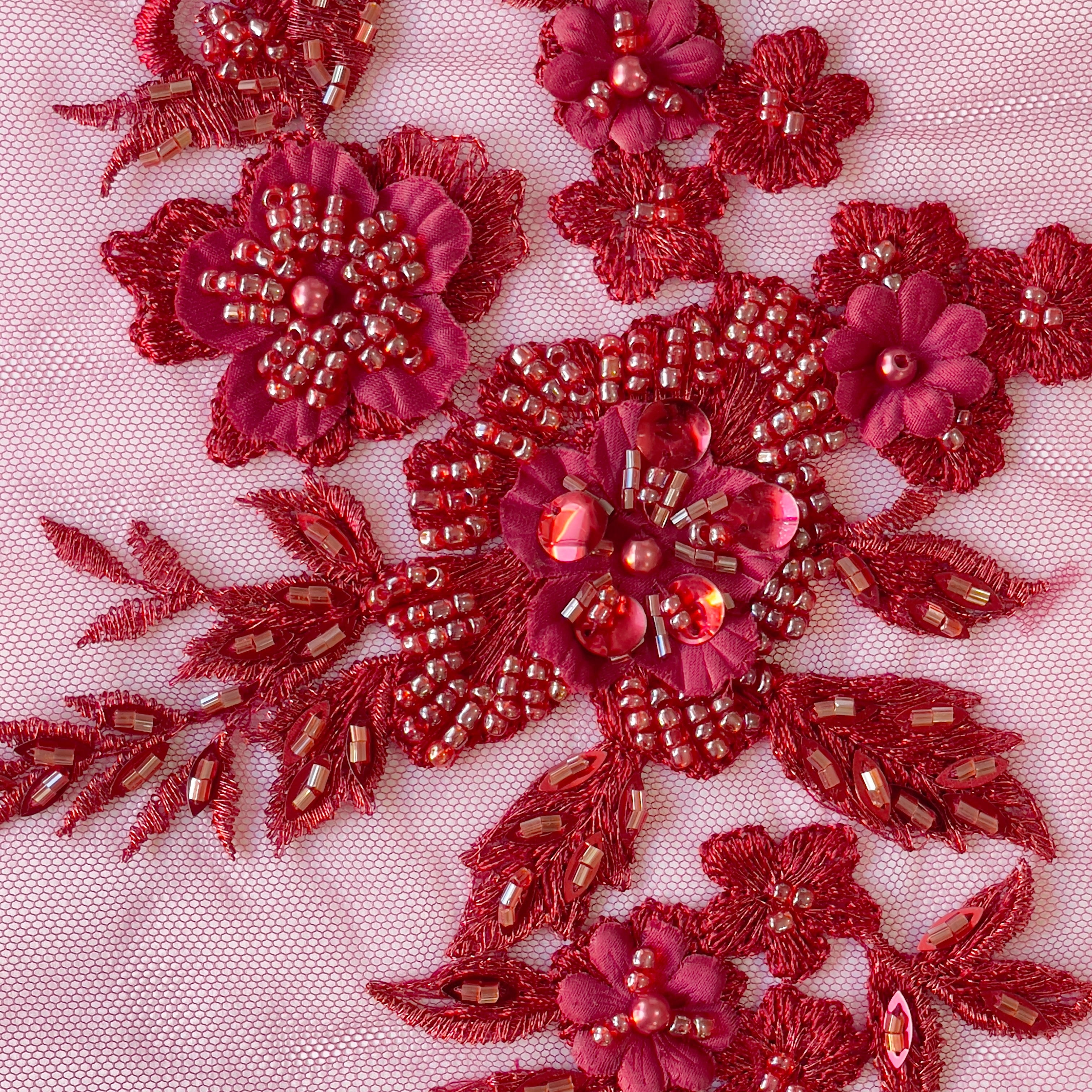 Close up view of floral applique embroidered onto a net backing.  The applique has #D flowers and is embellished with sequins and beads.