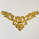 Single v-shaped gold bodice applique embellished with sequins laying flat on a white background.