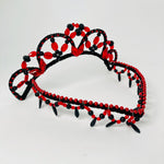 Side view of red and black Spanish style tiara featuring a v shaped forehead piece embellished with red metallic beads and red and black fringing. 
