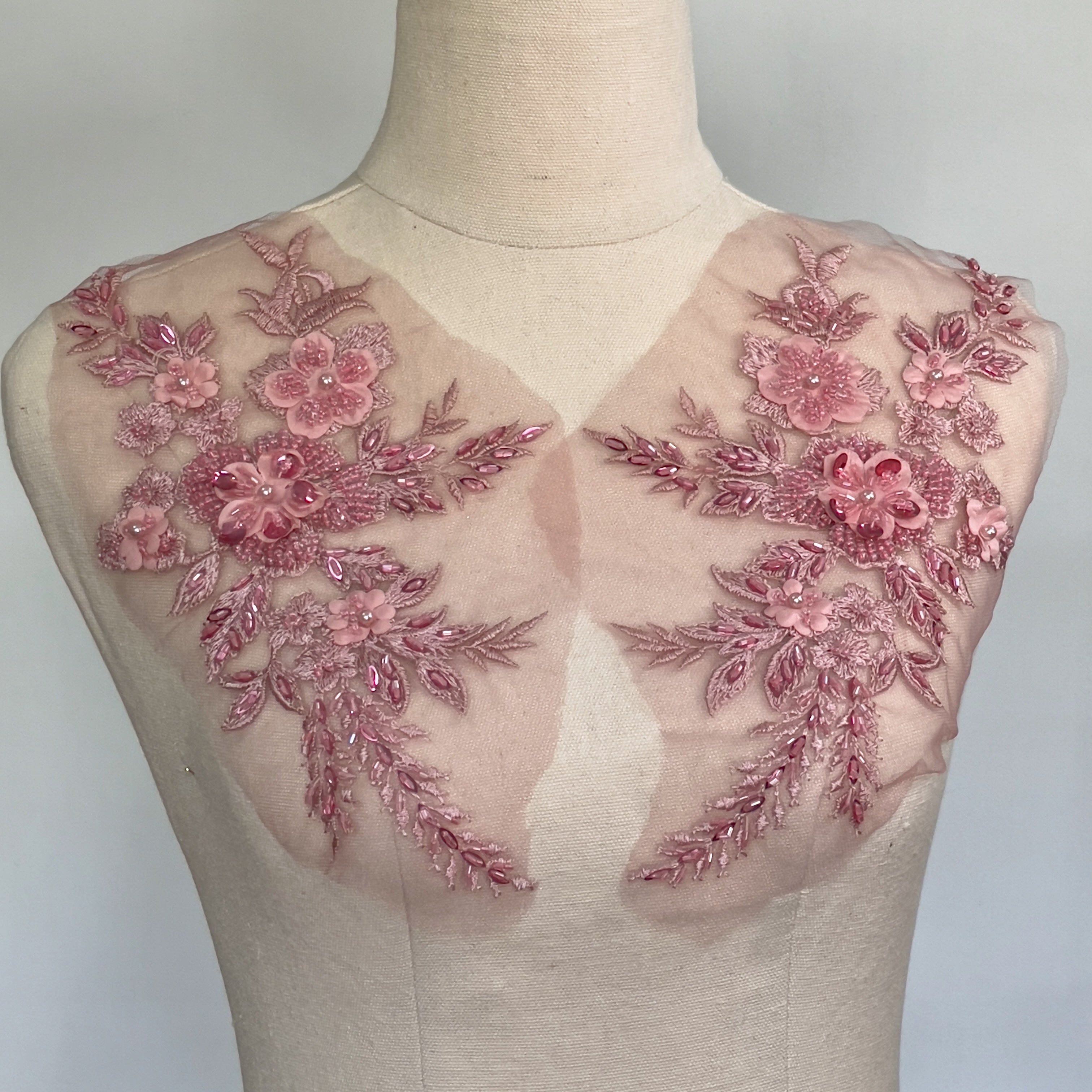 Dusty pink beaded floral applique pair displayed on a mannequin.