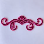 Single fuchsia sequin scroll bodice applique filed with fuchsia sequins and edged with fuchsia seed beads laying flat on a white background.