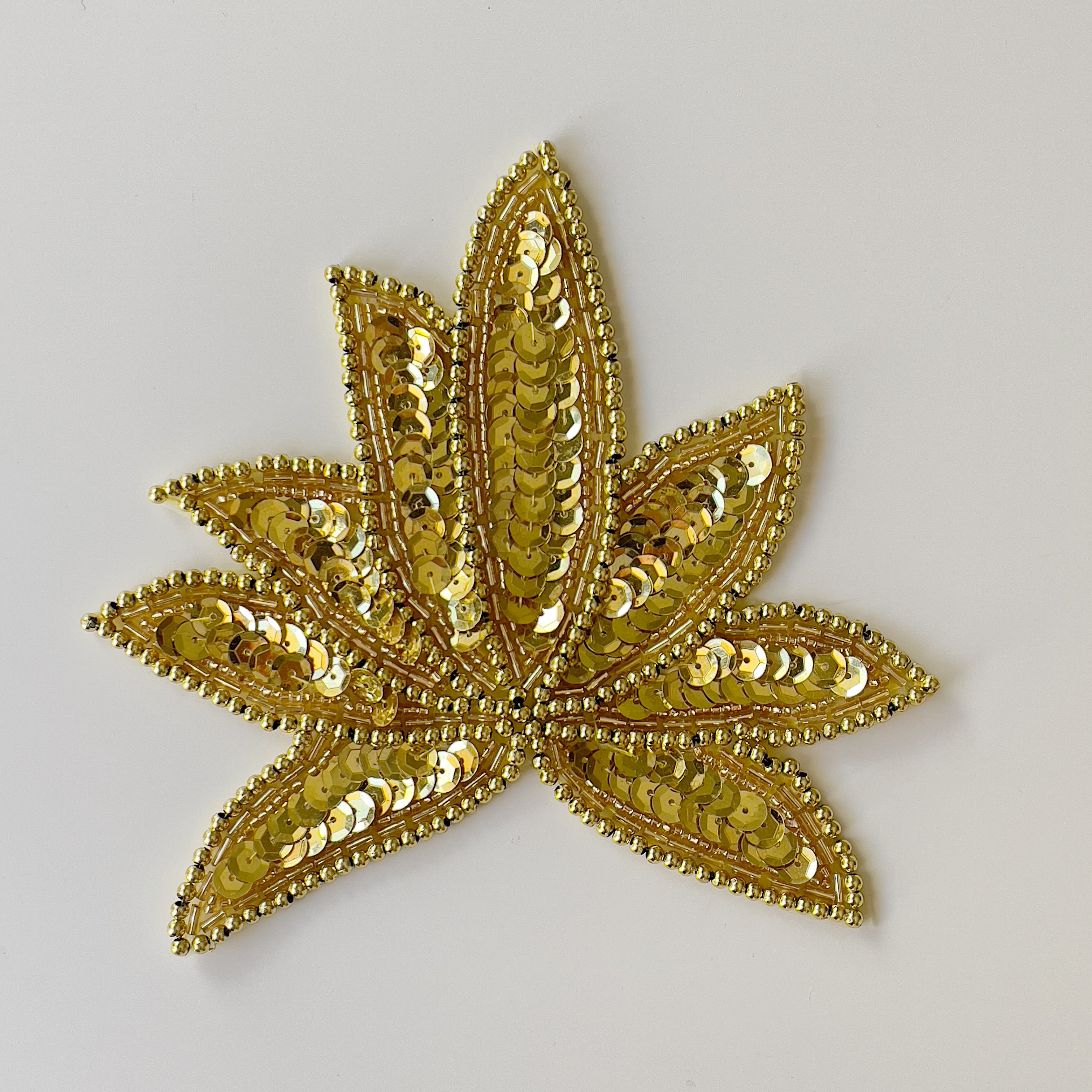 Gold leaf shaped applique.  Leaf shapes are filled with gold sequins and edged with gold beads.