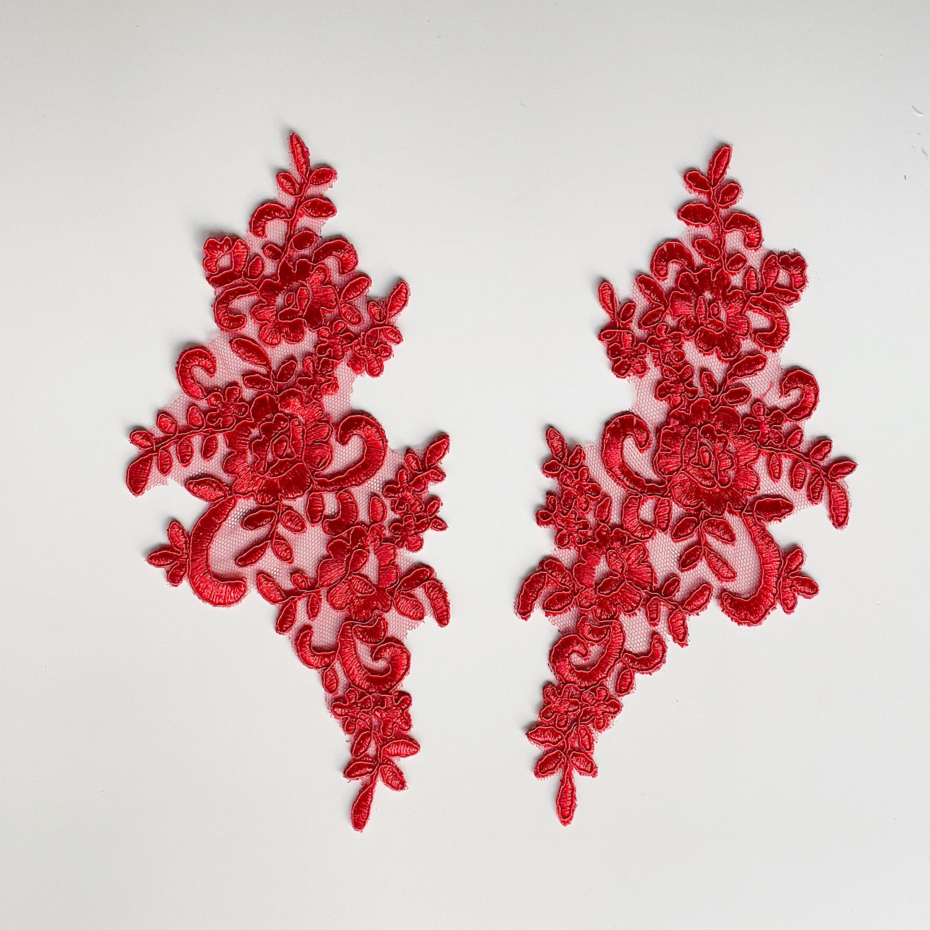 Tomato red floral embroidered and corded applique pair laying flat on a white background.
