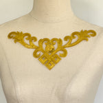 Single v-shaped gold bodice applique embellished with sequins displayed on a mannequin.