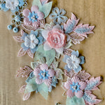 A closeup view of a pink sage green and blue applique with 3D flowers.
