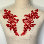 Red applique pair with a floral design.  The appliques are embroidered with red sequins and are displayed on a mannequin. 