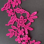 Close up view of rose pink embroidered lace applique with a floral design.